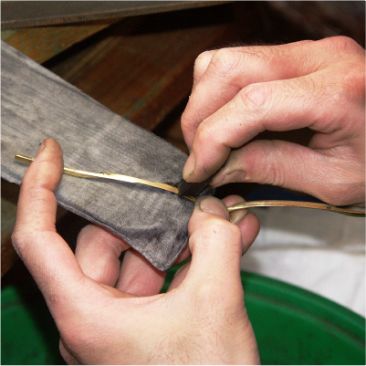 職人雙手以布輪拋光細長金屬眼鏡零件的近距離工作畫面