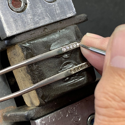 日本職人以工具在兩支貴金屬鏡腳上手工鑲嵌鑽石的製作過程特寫